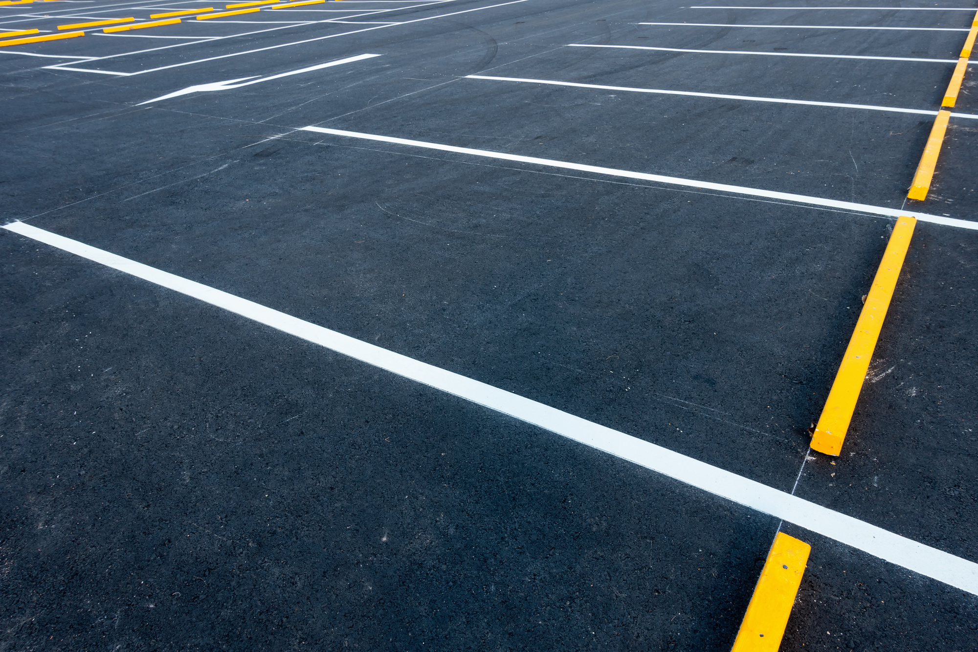 Freshly sealcoated commercial parking lot with crisp yellow striping in North Jersey